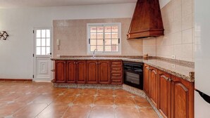A kitchen with wooden cabinets, a built-in oven, and a window with a view of the outside. - Beautiful Arianny House With Pool (Arona)