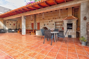 An outdoor patio with a brick wall, a stone oven, and outdoor seating. - Beautiful Arianny House With Pool (Arona)