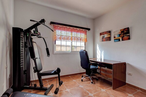 A room with a workout machine, a desk, and a chair. - Beautiful Arianny House With Pool (Arona)
