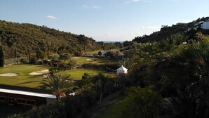 Ein Golfplatz mit Clubhaus, umgeben von üppigem Grün und Hügeln.