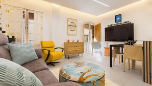 A modern living room with a sofa, yellow armchair, wooden cabinet, and a dining area with a table and chairs. - Magic Stay in Granada With Private Parking (Granada)