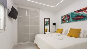 A modern hotel room with a large bed, a sliding door closet, a mounted TV, and a colorful abstract painting. - Magic Stay in Granada With Private Parking (Granada)