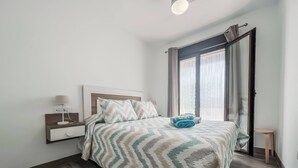 Une chambre à coucher moderne, avec un lit, une table de chevet, une lampe et une vue sur l’extérieur par une fenêtre.