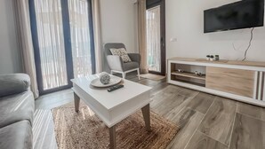 Un salon moderne comprenant un canapé, une table basse, un téléviseur et un meuble pour téléviseur.