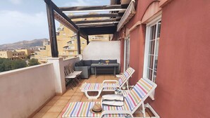 A balcony with white striped lounge chairs, a small table, and a sofa.