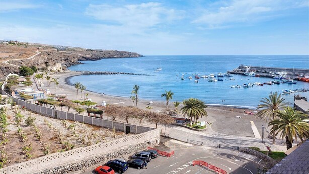 A coastal view with a marina, parked cars, and a clear sky. - Las Brisas Playa San Juan (Guia de Isora)