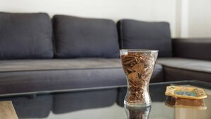 A glass vase with dried flowers on a glass table in a living room with a dark-colored sofa. - Las Brisas Playa San Juan (Guia de Isora)