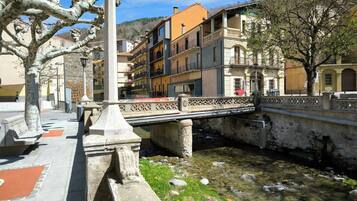 A stone bridge over a clear stream with buildings on either side.