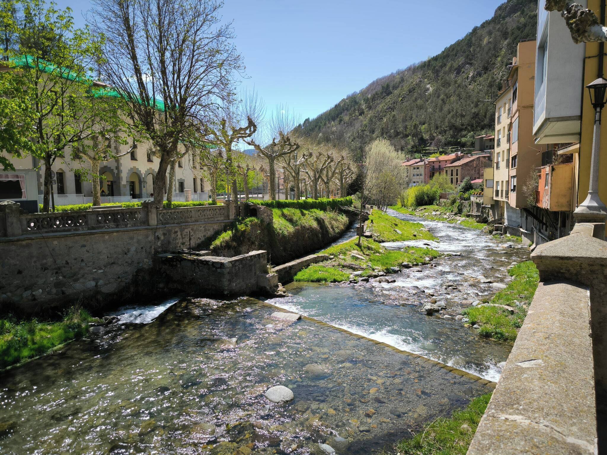 A river flowing through a town with stone bridges and buildings along the riverbank.