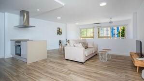Un espacio de estar moderno con cocina, sofá y mesa de comedor.