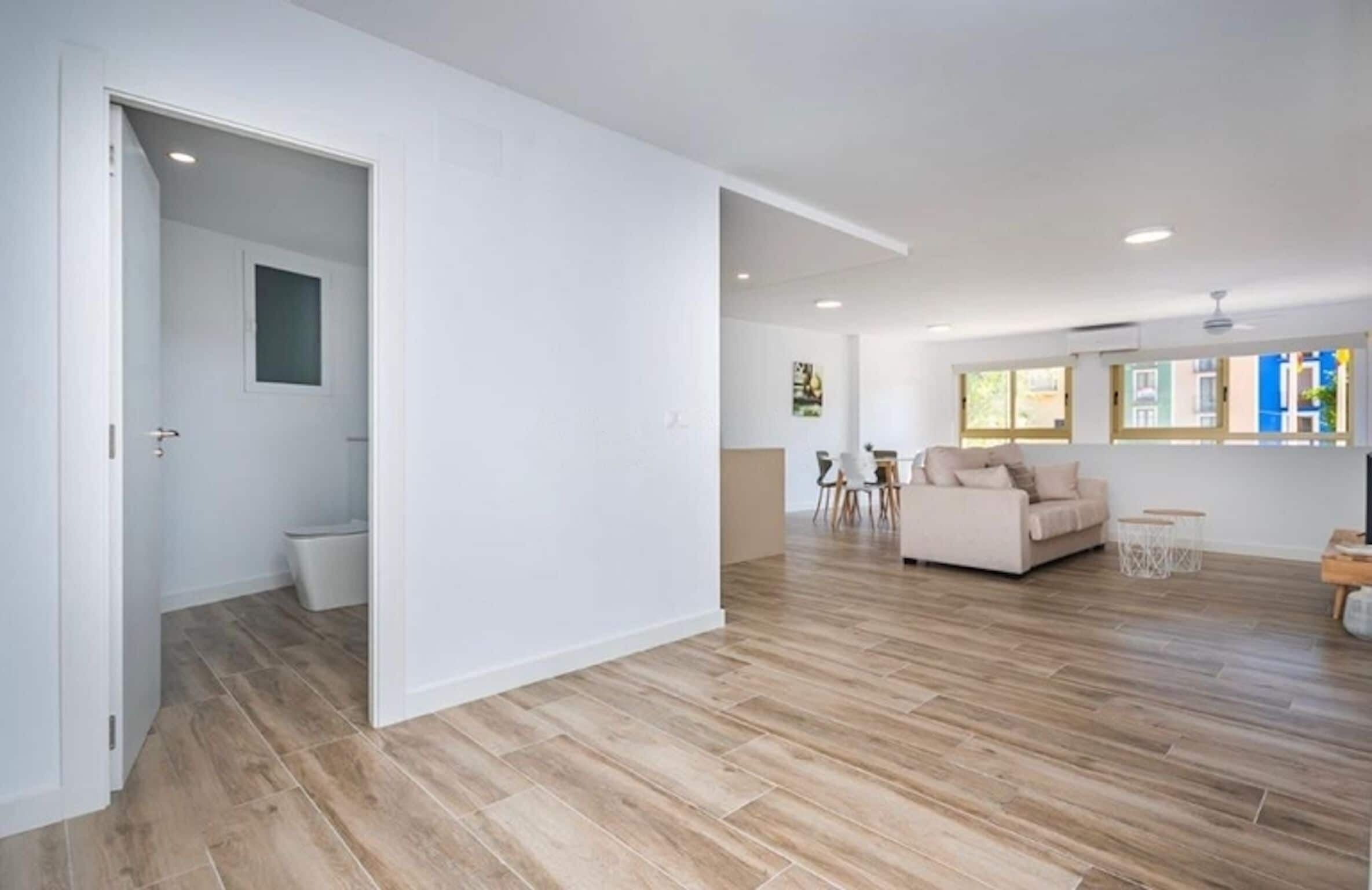 Un vaste espace de vie doté d’un plancher en bois, d’un canapé et d’une table à manger.