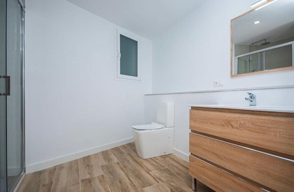 Une salle de bain avec des toilettes, un meuble-lavabo en bois et un miroir.