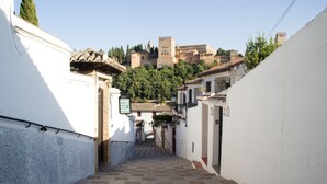 Une ruelle étroite, dont le sol est recouvert de carreaux, mène à un bâtiment surmonté d’un toit en tuiles.