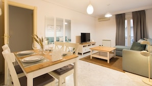 Un salon moderne comprenant un coin repas, un canapé, un téléviseur et une lampe.