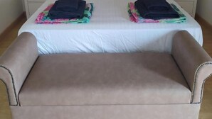 Una cama doble con sábanas blancas, dos mesitas de noche con lámparas y un cuadro sobre la cama.