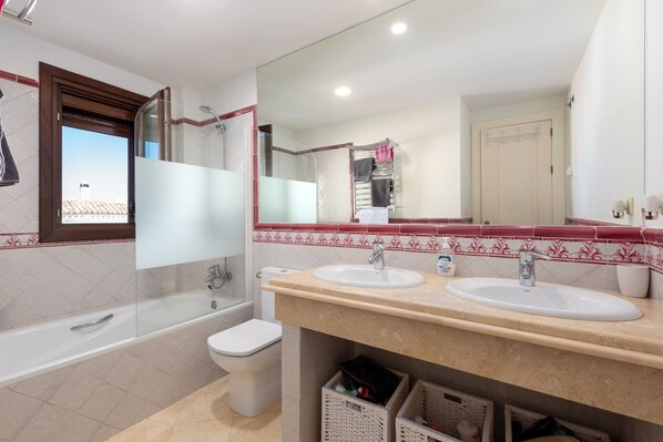 A bathroom with two sinks, a bathtub, and a toilet.