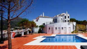 Un edificio blanco con piscina, rodeado de un patio con tejas rojas.