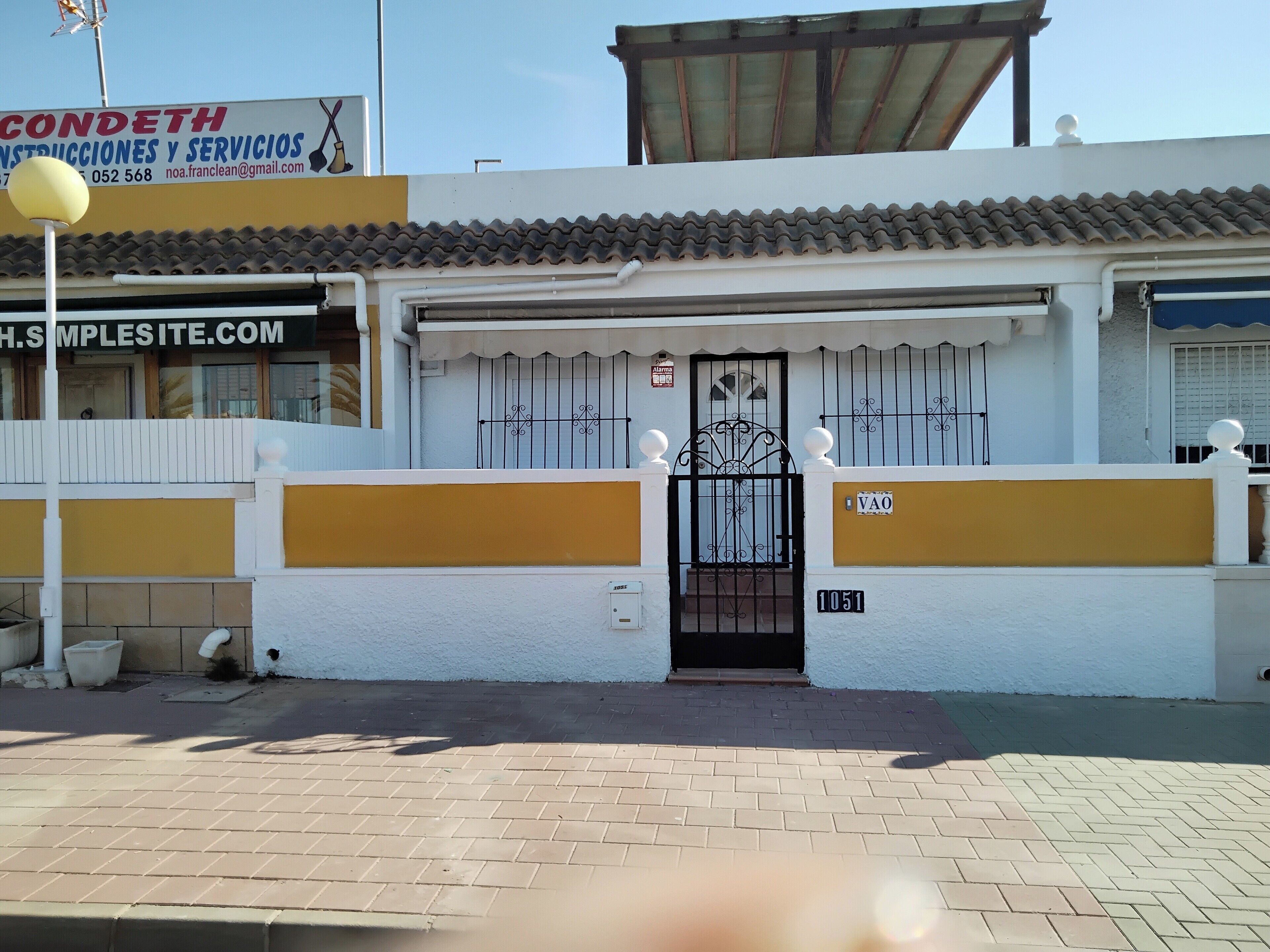 A building with a white facade, a tiled roof, and a gated entrance.