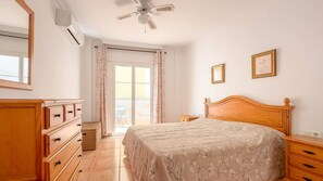 Quarto com cama, cômoda e ventilador de teto.
