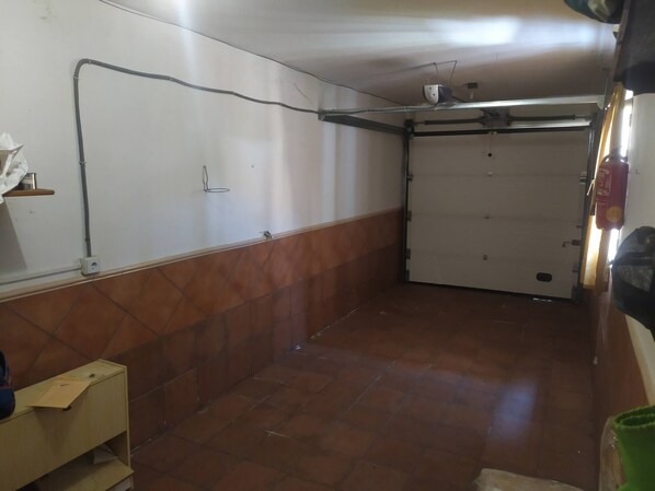 Une pièce avec un sol carrelé, une porte blanche et un mur avec une canalisation.