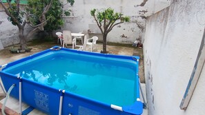 A rectangular swimming pool with a blue interior, surrounded by a white wall. There are white plastic chairs and a small tree in the background. - Room-habitación Privada Doble Toledo (Toledo)