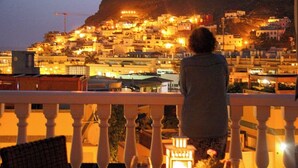 A balcony with a table set for dining, overlooking a hillside town at dusk. - Playa De Mogan Mirador 5 by El Sirocco (Mogan)