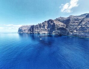 A coastal landscape with rocky cliffs and calm blue waters. - Costa Isora 1 Frontline (Guia de Isora)