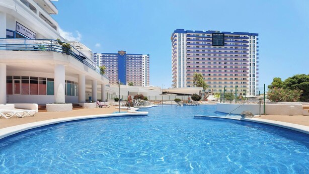 A swimming pool with lounge chairs and a building with balconies in the background. - 418 Panoramic View - Studio Located in Playa Paraíso (Adeje)