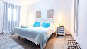 Una camera da letto con un letto, due comodini, un tavolo da notte, una finestra e una tenda.