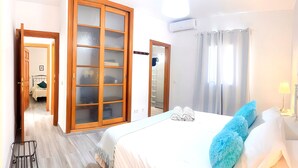A hotel room with a bed, a wardrobe, a mirror, and a bathroom visible through an open door. - Villa Descansa With Private Pool, Air-conditioning, Sea View, Smart-tv & Wifi (Yaiza)