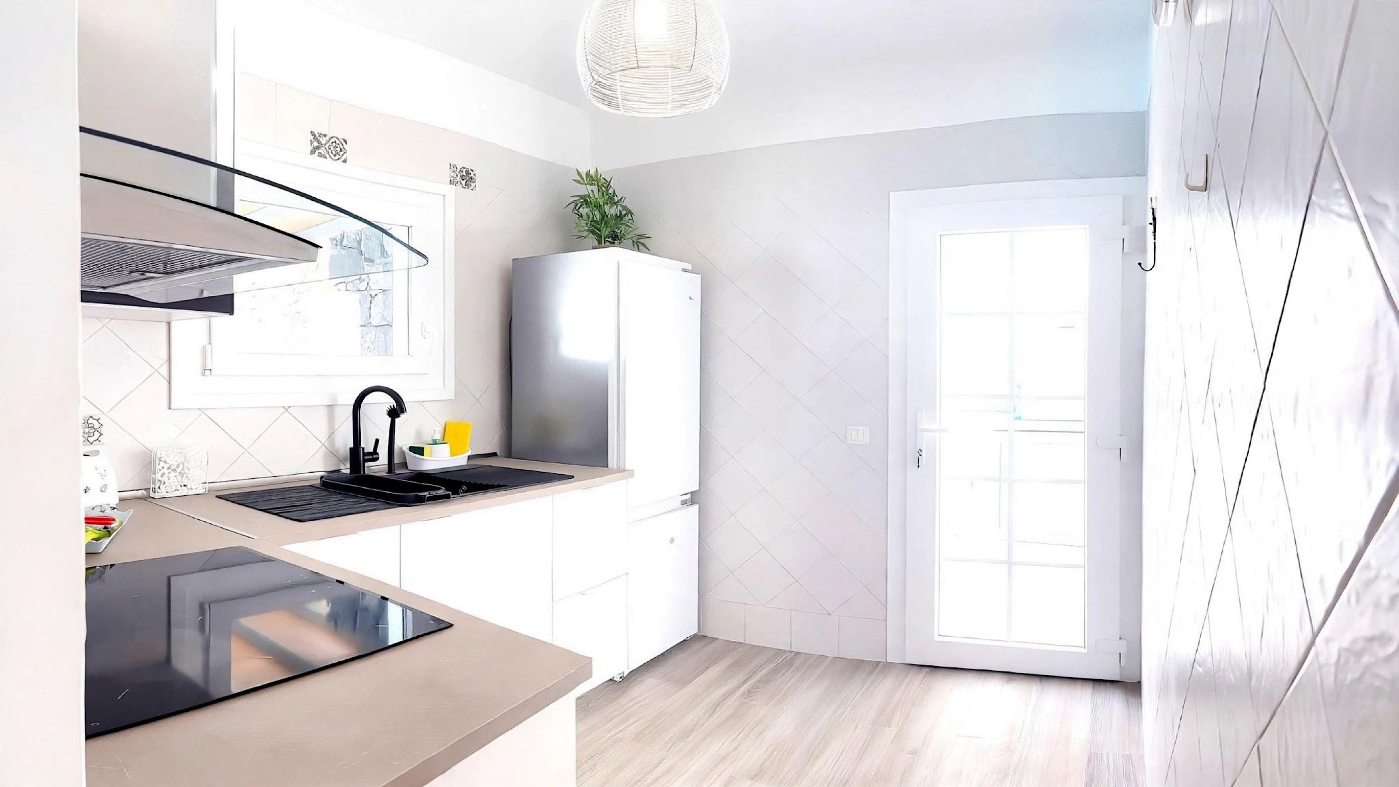 Une cuisine moderne équipée d’une cuisinière intégrée, d’un évier avec un robinet et d’un meuble blanc.