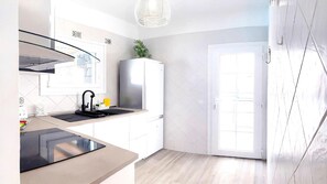 A modern kitchen with a built-in stove, a sink with a faucet, and a white cabinet. - Villa Descansa With Private Pool, Air-conditioning, Sea View, Smart-tv & Wifi (Yaiza)