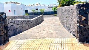 A paved pathway leading to a building with white walls and stone walls. - Villa Descansa With Private Pool, Air-conditioning, Sea View, Smart-tv & Wifi (Yaiza)
