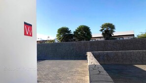 A paved outdoor area with a stone wall and a building in the background. - Villa Descansa With Private Pool, Air-conditioning, Sea View, Smart-tv & Wifi (Yaiza)