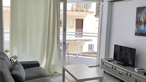 A living room with a sofa, a coffee table, a TV, and a balcony with a view of buildings. - Stunning two Bedroom Apartment in Salou (Salou)