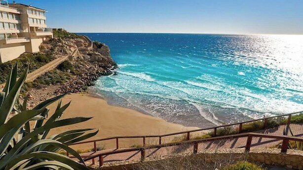 A coastal hotel with a beach view, a staircase leading to the beach, and a railing along the path. - Stunning two Bedroom Apartment in Salou (Salou)