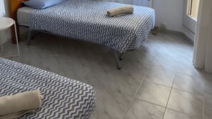 A small, clean room with a single bed, a small table, and a window with a view of the outside. - Stunning two Bedroom Apartment in Salou (Salou)