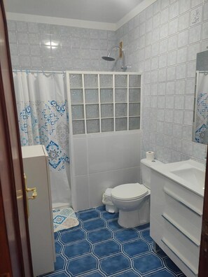 Un baño con inodoro, lavabo y ducha.