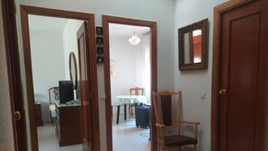 Um corredor com portas de madeira, uma sala de jantar com mesa e cadeiras, e um espelho na parede.