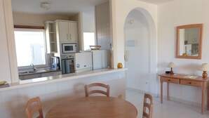 A compact kitchen with a dining area, including a table and chairs, a small cabinet, and a microwave. - Beautiful 2 Bedroom, 2 Bathroom Apartment (Roquetas de Mar)