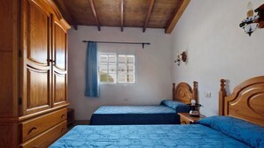 A bedroom with two beds, wooden wardrobe, and a window with curtains. - House El Cardón A1 in Buenavista del Norte (Buenavista del Norte)