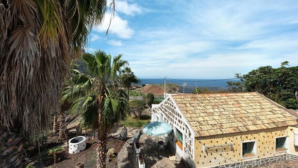 A house with a tiled roof, a patio with a table and chairs, and a view of the ocean. - House El Cardón A1 in Buenavista del Norte (Buenavista del Norte)