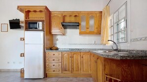 A kitchen with wooden cabinets, a built-in microwave, a stove, and a sink. - House El Cardón A1 in Buenavista del Norte (Buenavista del Norte)