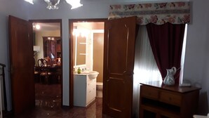 A room with a bed, a wooden dresser, a bathroom with a sink and toilet, and a dining area with chairs and a table. - Spacious and Cozy Attic to Rest and Enjoy (Los Silos)