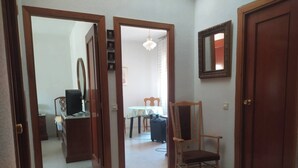 A hallway with a wooden chair, a desk with a computer, and a dining area with a table and chairs. - Room-double Bunk Room Toledo (Toledo)