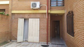 A courtyard with a brick building, a closed door, and an air conditioning unit mounted on the wall. - Room-double Bunk Room Toledo (Toledo)