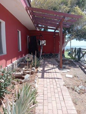 A red building with a brick pathway leading to a covered outdoor area. - Sunset and Oceanview 1 Bedroom Apartment With Shared Pool (San Bartolomé de Tirajana)