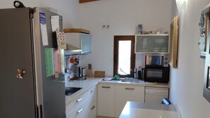 Una cucina con frigorifero, forno a microonde e travi in legno a soffitto.
