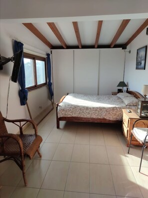 A bedroom with a bed, a chair, a nightstand, a lamp, and a window with curtains. - Sunset and Oceanview 1 Bedroom Apartment With Shared Pool (San Bartolomé de Tirajana)