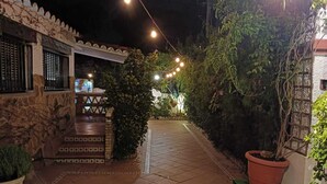 Un chemin pavé mène à un bâtiment aux murs en pierre et à une entrée carrelée.